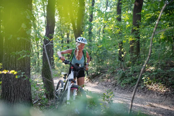 アクティブシニア女性バイカー推進ebike屋外で森の中. — ストック写真