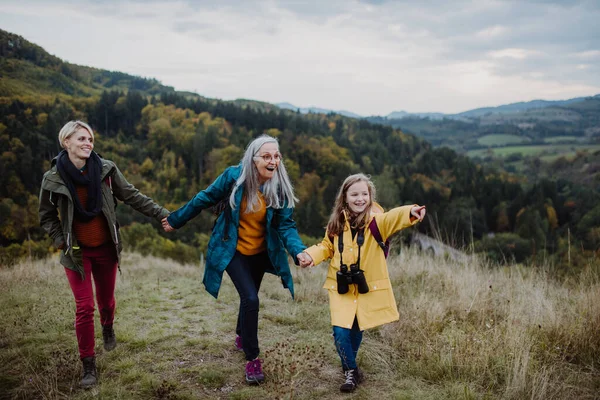 Small girl with mother and grandmother hiking outoors in nature. — Stock Photo, Image