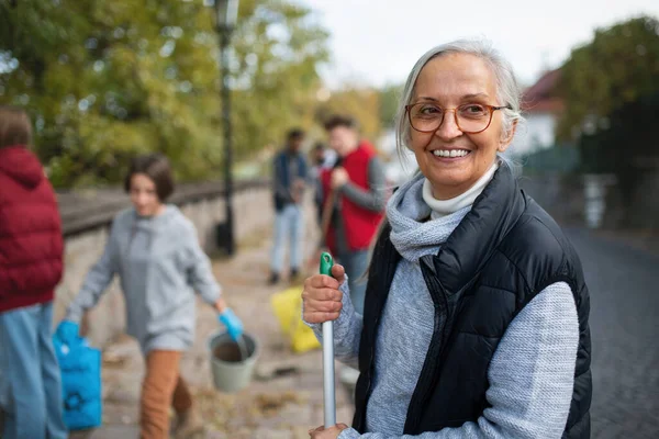 Senior kvinna volontär med laget städa upp gatan, samhällstjänst koncept — Stockfoto