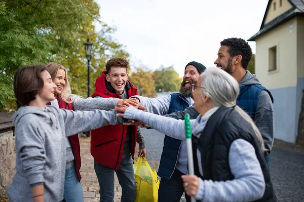 Různorodá skupina šťastný komunitní služby dobrovolníci stohování ruce dohromady venku na ulici — Stock fotografie