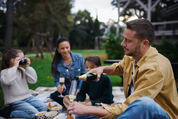 Glad ung familj sitter på filt och har tagit bort picknick utomhus i restaurang område. — Stockfoto