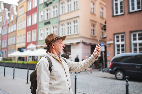 Портрет счастливого пожилого человека туриста, делающего селфи на открытом воздухе в историческом городе — стоковое фото