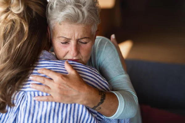 Adult daughter consoling unhappy senior mother and supporting her in struggle indoors at home. — Stock Photo, Image