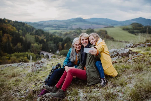 Small girl with mother and grandmother taking selfie outoors on top of mountain. — Stock Photo, Image