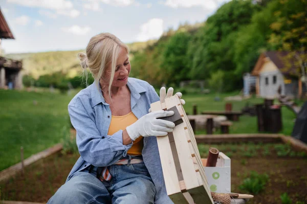 Happy senior woman renovating wooden crate outdoors in garden. — Stock Photo, Image