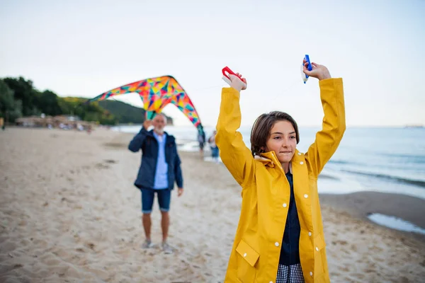 สาววัยรุ่นที่มีความสุขและปู่ของเธอเล่นกับว่าวบนชายหาดทราย . — ภาพถ่ายสต็อก