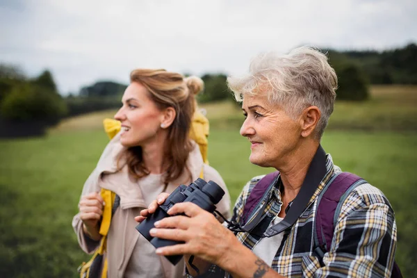 Feliz senderista madre mayor con hija adulta sosteniendo prismáticos al aire libre en la naturaleza — Foto de Stock