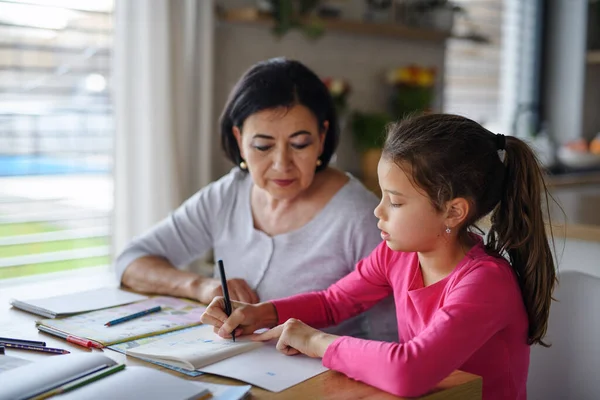 Liten flicka med mormor gör läxor inomhus hemma. — Stockfoto