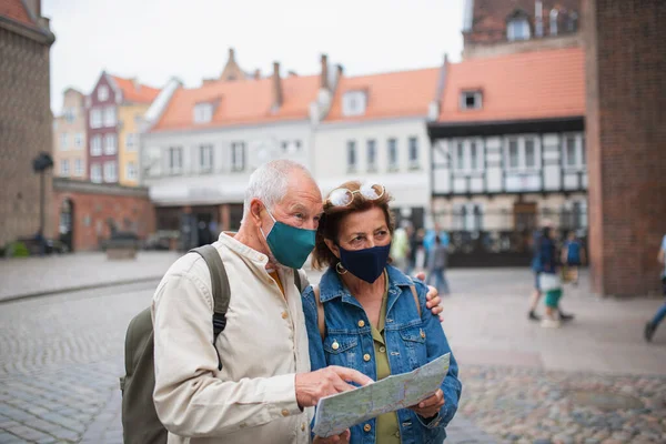 Ηλικιωμένοι τουρίστες ζευγάρι με μάσκες προσώπου χρησιμοποιώντας το χάρτη σε εξωτερικούς χώρους στο δρόμο της πόλης — Φωτογραφία Αρχείου