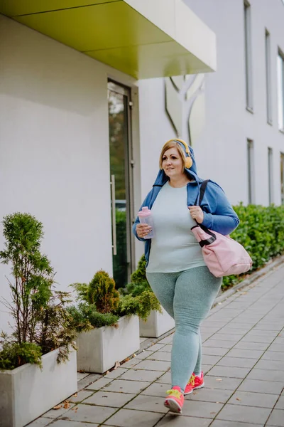 Gelukkig overgewicht vrouw in sport kleding buiten op weg naar fitness centrum — Stockfoto
