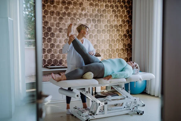 Metà donna fisioterapista adulto che esercita con la donna in sovrappeso al chiuso nel centro di riabilitazione — Foto Stock