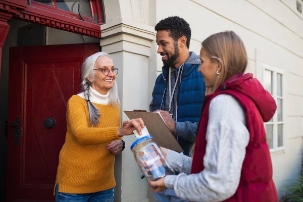 Jóvenes recaudadores de fondos puerta a puerta hablando con mujeres mayores y recaudando dinero para caridad en la calle. — Foto de Stock