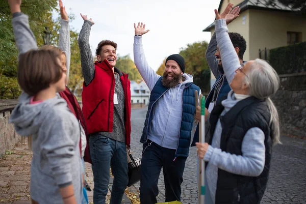 Diverso grupo de voluntários de serviço comunitário feliz levantando as mãos juntos ao ar livre na rua — Fotografia de Stock