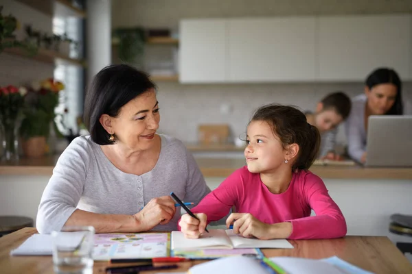 Klein meisje met oma doen huiswerk binnen thuis. — Stockfoto