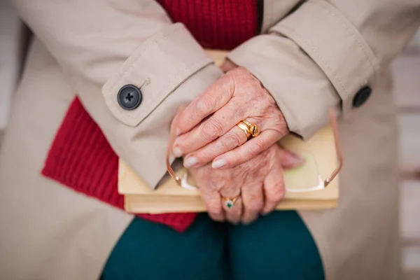 Großaufnahme einer eleganten Seniorin, die ein Buch in der Hand hält und draußen auf einer Bank sitzt. — Stockfoto