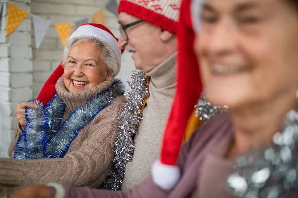 Счастливые старшие друзья сидят в помещении общинного центра и празднуют Рождество. — стоковое фото