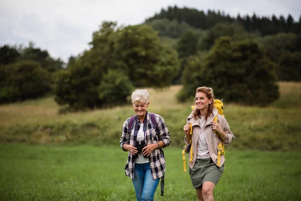 Aktive Seniorin mit Fernglas wandert mit ihrer erwachsenen Tochter in der Natur. — Stockfoto