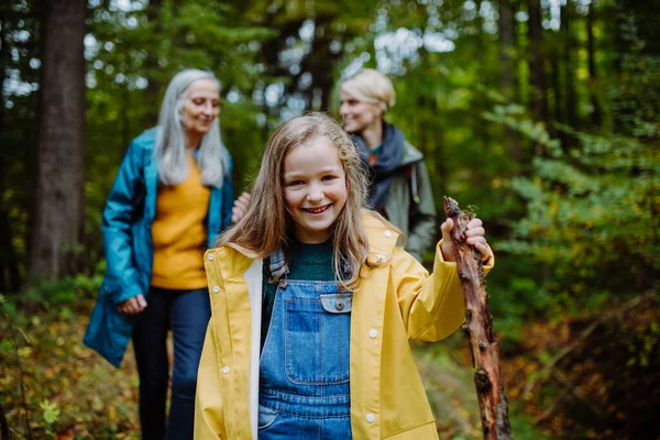 Annesi ve büyükannesiyle birlikte ormanda yürürken kameraya bakan mutlu küçük kız. — Stok fotoğraf