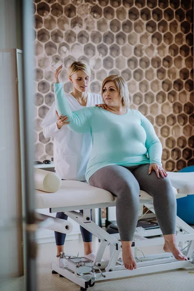 Mitte erwachsene Physiotherapeutin trainiert mit übergewichtiger Frau im Reha-Zentrum — Stockfoto