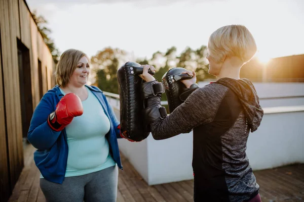 Übergewichtige Frau trainiert Boxen mit Personal Trainer draußen auf der Terrasse. — Stockfoto