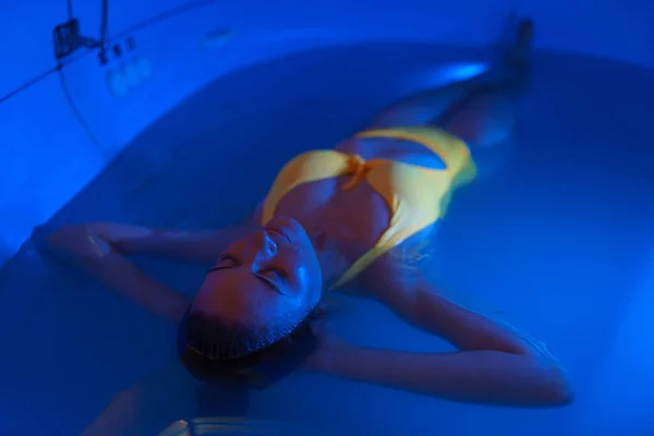 Schöne Frau schwimmt im mit dichtem Salzwasser gefüllten Tank, der in der medizinischen Therapie verwendet wird. — Stockfoto
