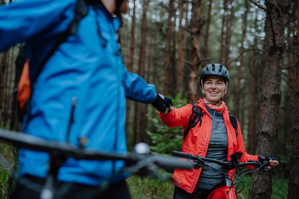 Senior couple bikers fist bumping outdoors in forest in autumn day. — Stockfoto
