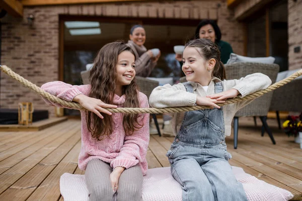 Two happy sisters with mother and grandmother sitting outdoors in patio in autumn. — Fotografia de Stock