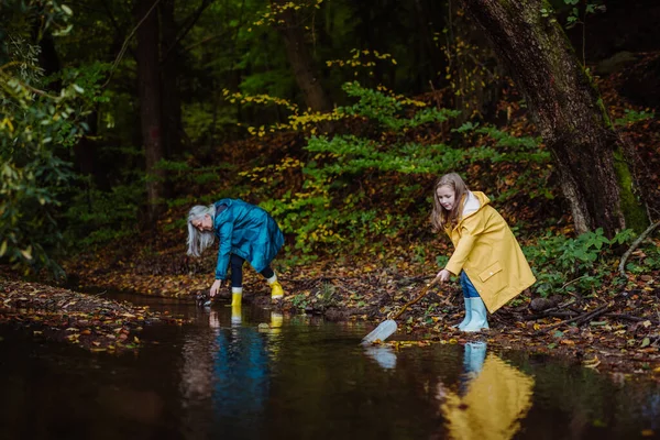 Petite fille avec grand-mère ramasser les déchets de petits lacs extérieurs dans la forêt. — Photo