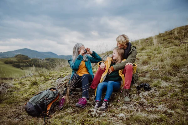 Senior woman taking picture of her daughter and granddaughter on top of hill in autumn day. — Zdjęcie stockowe