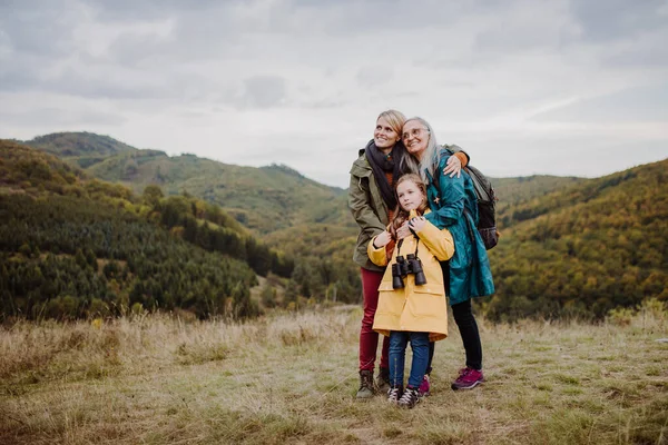Small girl with mother and grandmother standing and lookiong at view on top of mountain. — Stockfoto