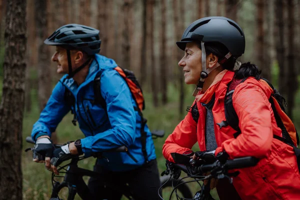 Coppia di motociclisti anziani con e-bike ammirare la natura all'aperto nella foresta in autunno giorno. — Foto Stock