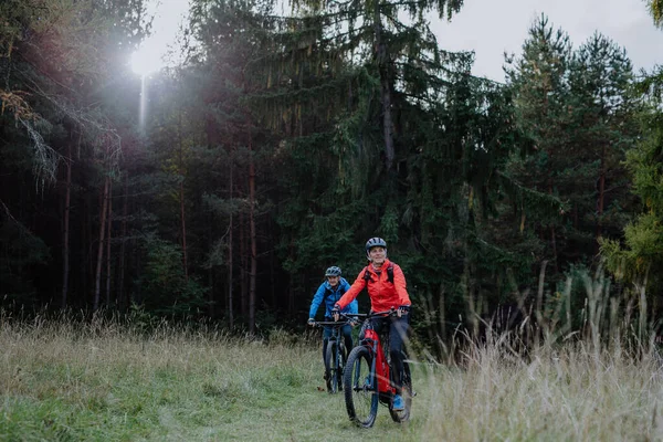 Actief seniorenpaar fietsen buiten in het bos in de herfst dag. — Stockfoto