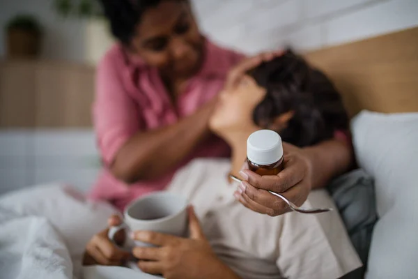 Madre cuidando a su hijo enfermo en casa. — Foto de Stock