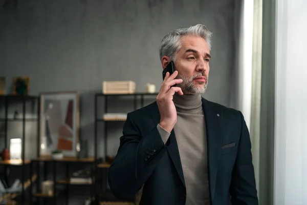 Uomo d'affari maturo che fa una telefonata in ufficio, distogliendo lo sguardo. — Foto Stock