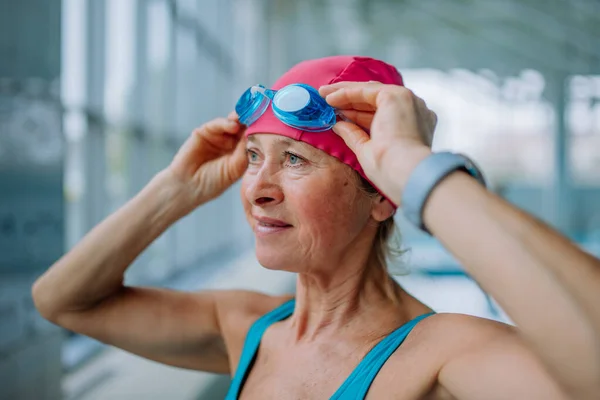 Close-up van senior vrouw zetten op bril voor zwemmen in binnen zwembad. — Stockfoto