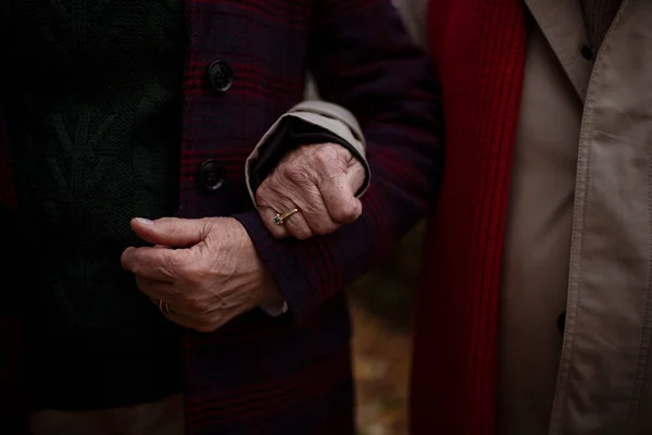 Nahaufnahme eines älteren Ehepaares, das sich bei einem Spaziergang im Herbst in der Stadt die Hände hält. — Stockfoto