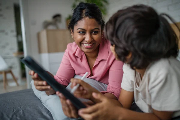 Madre india usando tableta con su hijo pequeño y divirtiéndose en casa. — Foto de Stock