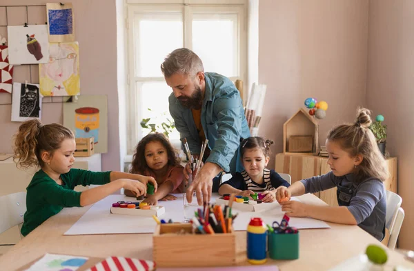 Grupo de niños pequeños que trabajan en el proyecto con el profesor durante la clase de arte creativo y artesanía en la escuela. — Foto de Stock