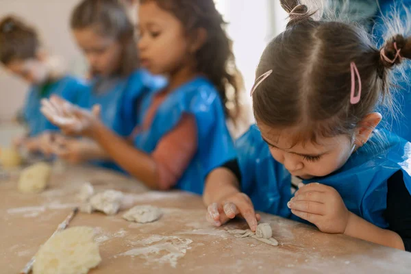Groep van kleine kinderen die werken met aardewerk klei tijdens creatieve kunst en ambachtelijke lessen op school. — Stockfoto