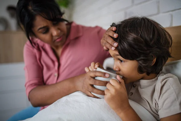 Mother taking care of her ill son at home. — Stock Photo, Image