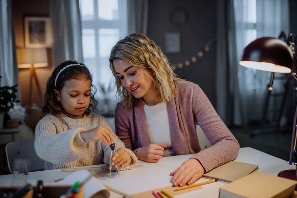 Ibu membantu putrinya mengerjakan PR, menggambar lingkaran dengan comasses di malam hari di rumah. — Stok Foto