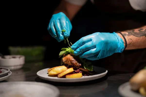 Cuochi mani in guanti che servono e decorano pasto in cucina ristorante — Foto Stock