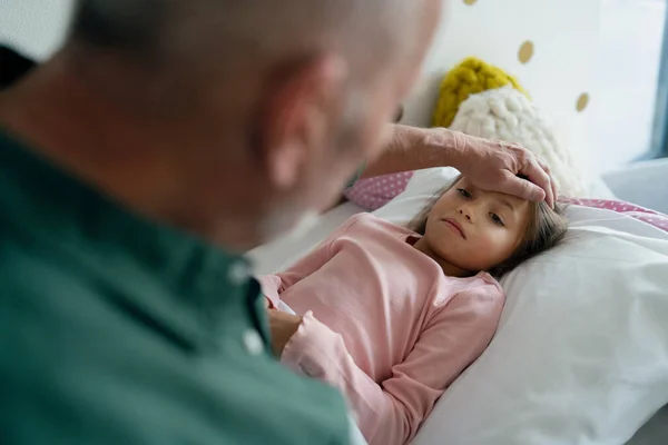 Abuelo cuidando de su nieta enferma acostada en la cama. — Foto de Stock