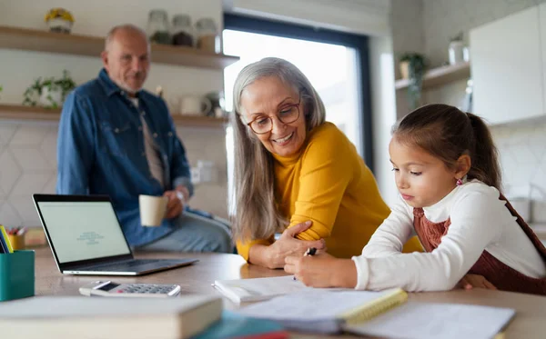 Klein meisje met senior grootouders doen wiskunde huiswerk thuis. — Stockfoto