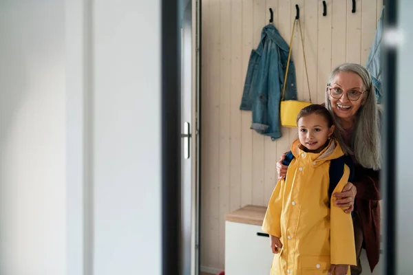Grandmother helping granddaughter to get ready to leave home for school. — Stock Photo, Image