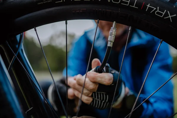 Primer plano de un hombre bombeando rueda de bicicleta en la naturaleza. — Foto de Stock