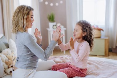 Mutlu anne ve küçük kızı evde el çırpma oyunu oynuyorlar..
