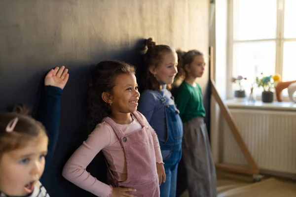 Группа маленьких девочек позирует перед школьной стеной картины в помещении в игровой комнате. — стоковое фото