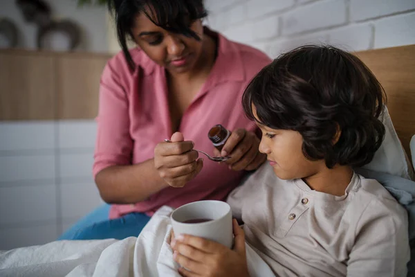 Pojken tar medicin från sin mamma hemma.. — Stockfoto