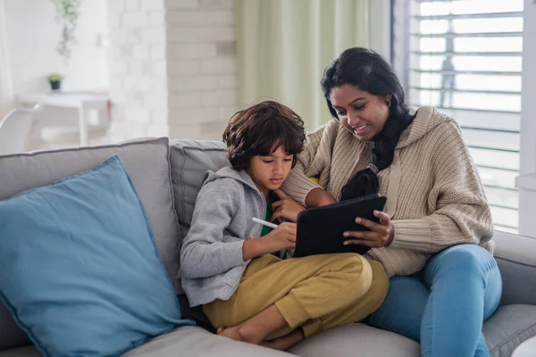 Indiase moeder met behulp van tablet met haar kleine zoon en plezier hebben thuis. — Stockfoto